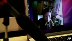 FILE - Tibetan and activist Poet Tsering Woeser appears on computer screen, top, during online video chat with The Associated Press, Beijing, March 1, 2012.