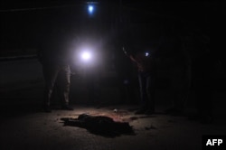 FILE - Somali security officers look at the body of a suspected al-Shabab fighter in Mogadishu, Somalia, Nov. 5, 2016. The U.S. military says 18 al-Shabab members were killed in an airstrike in southern Somalia.