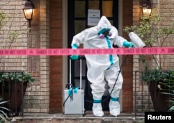 A member of the CG Environmental HazMat team disinfects the entrance to the residence of a health worker at the Texas Health Presbyterian Hospital who has contracted Ebola in Dallas, Texas, Oct.12, 2014.