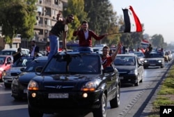 Hundreds of Syrians wave national flags and chant slogans against U.S. President Trump, April 14, 2018, following a wave of U.S., British and French military strikes to punish President Bashar Assad for suspected chemical attack against civilians.