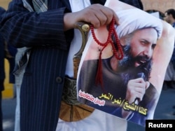 FILE - A Shi'ite protester carries a poster of Sheikh Nimr al-Nimr during a demonstration outside the Saudi embassy in Sanaa, Oct. 18, 2014.