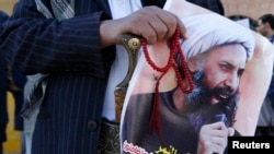 A Shi'ite protester carries a poster of Sheikh Nimr al-Nimr during a demonstration outside the Saudi embassy in Sanaa, Oct. 18, 2014. 