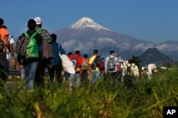 Central American migrants begin their morning trek as part of a thousands-strong caravan hoping to reach the U.S. border, as they face the Pico de Orizaba volcano upon departure from Cordoba, Mexico, Monday, Nov. 5, 2018.