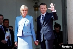 French President Emmanuel Macron and his wife, Brigitte Trogneux, wave to former President Francois Hollande as he leaves after the handover ceremony at the Elysee Palace in Paris, May 14, 2017.