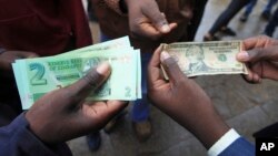 FILE: Zimbabweans compare the new note with the U.S. dollar note following the introduction of new notes by the Reserve Bank of Zimbabwe in Harare, Nov, 28, 2016. 