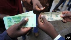 Zimbabweans compare the new note with the U.S. dollar note following the introduction of new notes by the Reserve Bank of Zimbabwe in Harare, Nov, 28, 2016. 