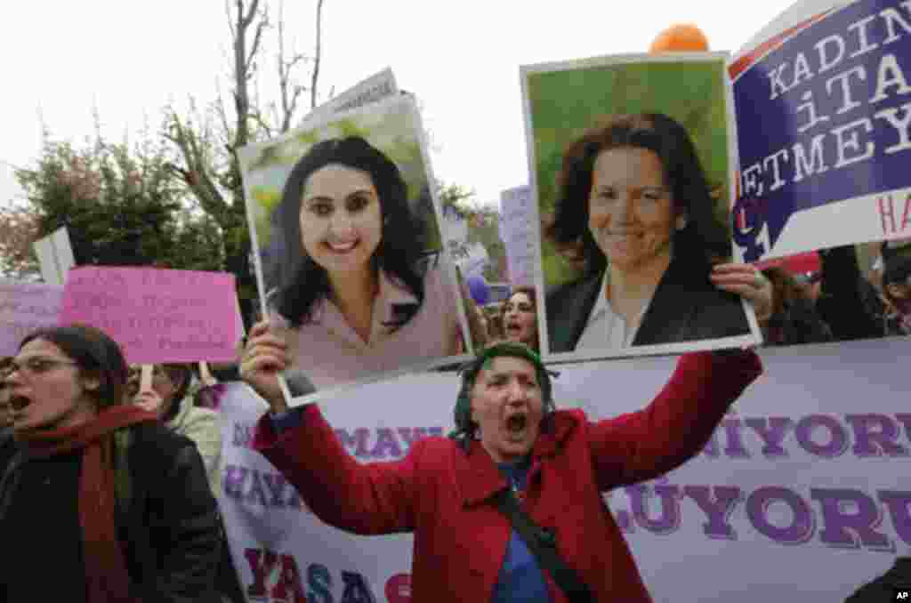 Une femme tient une pancarte avec des images de législatrices pro-kurdes emprisonnées Figen Yuksekdag, à gauche, et Selma Irmak lors de la Journée internationale des droits des femmes à Ankara, en Turquie, le jeudi 8 mars 2018.