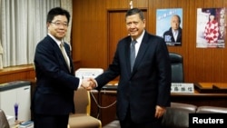 일본을 방문 중인 마르주키 다루스만 유엔 북한인권특별보고관(오른쪽)이 18일 도쿄에서 가토 가쓰노부 납치문제 담당상과 만나 악수하고 있다.