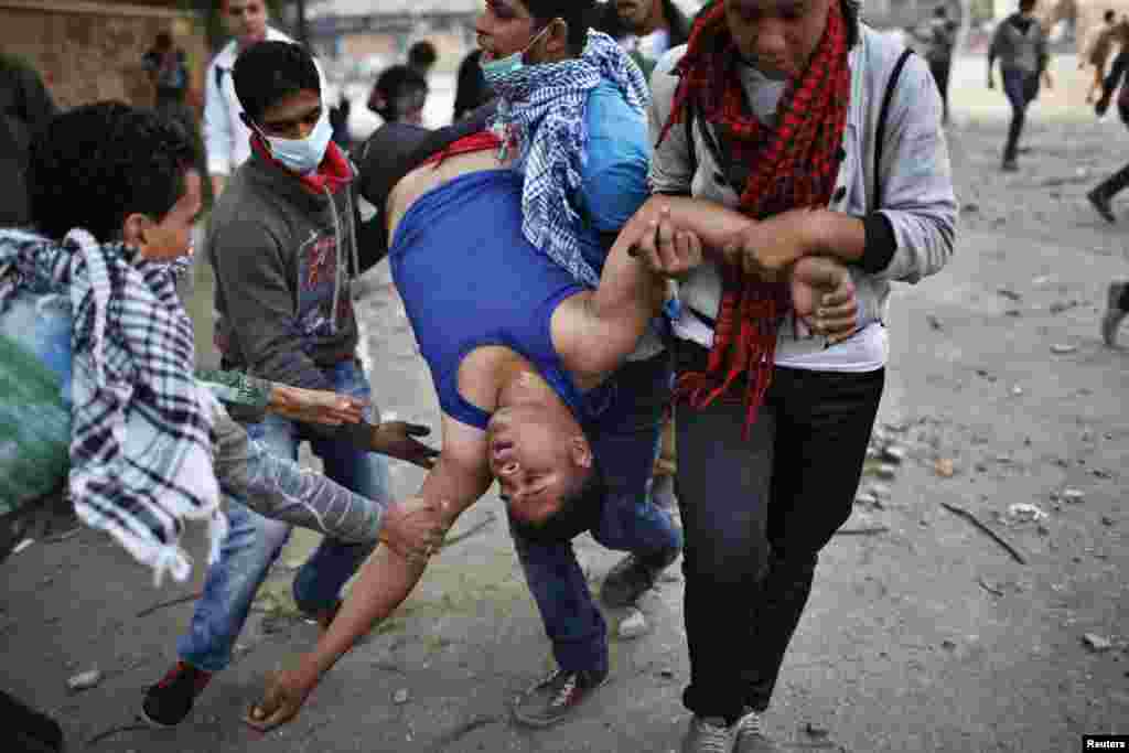 Anti-Morsi protesters carry a wounded man away from tear gas during clashes with riot police at Tahrir square in Cairo November 27.