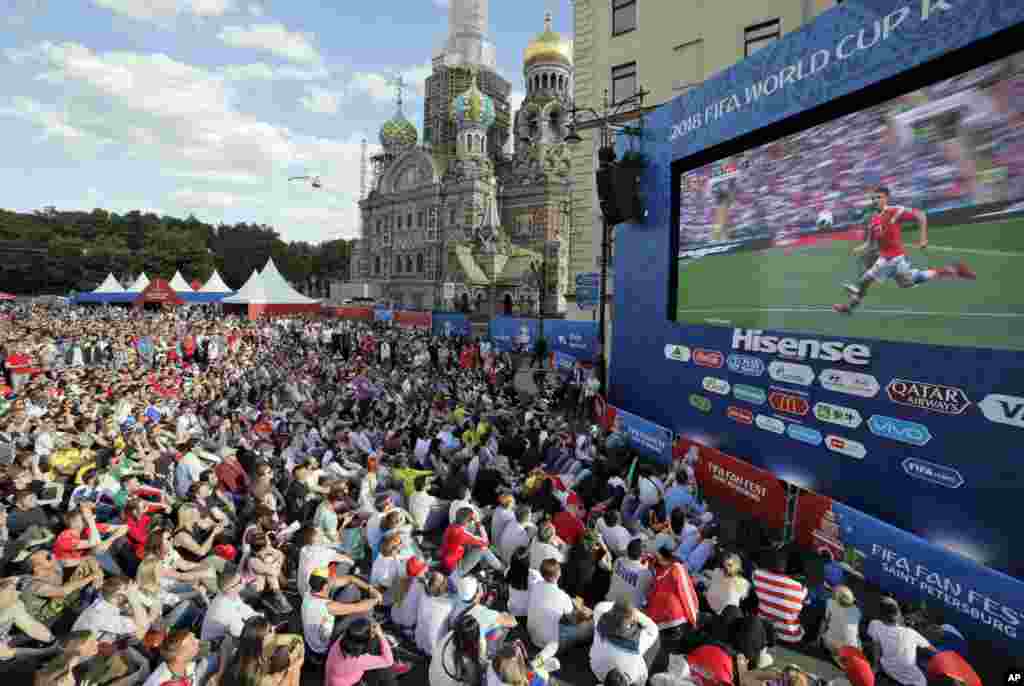 People watch the 2018 soccer World Cup match between Russia and Saudi Arabia on a huge screen at a fan zone in St. Petersburg, Russia.