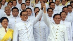 FILE - Cambodian opposition leader Sam Rainsy (C-L) raises hands with Kem Sokha (C-R), deputy of Cambodia National Rescue Party (CNRP) in front of members of parliament before the swearing in ceremony inside the Royal Palace in Phnom Penh on August 5, 2014. (AFP)