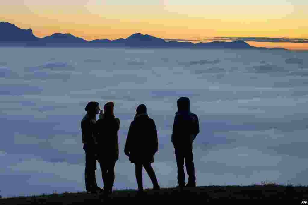 People enjoy the view of heavy fog hanging over Lake Geneva in Riex near Lausanne, western Switzerland.