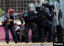 Riot police take cover during clashes with university students protesting over a controversial reform to the pension plans of the Nicaraguan Social Security Institute in Managua, Nicaragua, April 20, 2018.