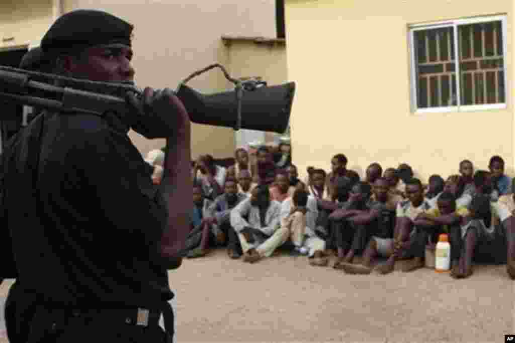 Policeman stand guard as suspected rioters await a court hearing in Kaduna, Nigeria, April 20, 2011