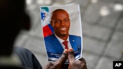 FILE - A person holds a photo of late Haitian President Jovenel Moise during his memorial ceremony at the National Pantheon Museum in Port-au-Prince, Haiti, July 20, 2021. 
