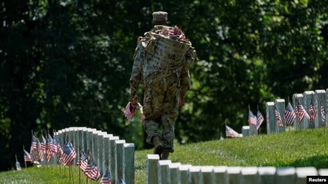 Una oficial de la "Vieja Guardia" participa en "Flags-In", un evento anual donde se coloca una pequeña bandera estadounidense frente a las lápidas de miembros del servicio de EE.UU. enterrados en el Cementerio Nacional de Arlington,en Virginia. Foto: Reuters.