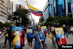 A nun carries Venezuelan flag next to demonstrators carrying homemade shields with religious images, during a rally against Venezuelan President Nicolas Maduro's government in Caracas, Venezuela, June 7, 2017