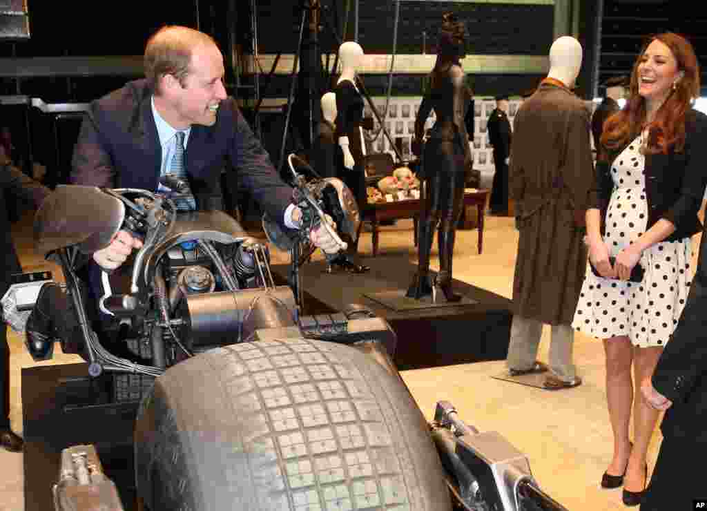 Britain's Kate, the Duchess of Cambridge, watches her husband Prince William as he sits on the 'Batpod' during the inauguration of "Warner Bros. Studios Leavesden" near Watford, approximately 18 miles north west of central London.