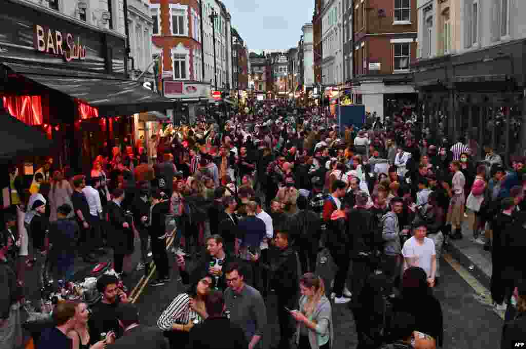 People pack a street outside bars in the Soho area of London, July 4, 2020, as restrictions are further eased during the novel coronavirus COVID-19 pandemic.