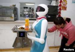 A woman input orders for a robot which works as a waitress in a restaurant in Xi'an, Shaanxi Province, China, April 20, 2016.