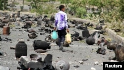 FILE - A boy walks on a street littered with cooking gas cylinders after a fire and explosions destroyed a nearby gas storage during clashes between fighters of the Popular Resistance Committees and Houthi fighters, in Yemen's southwestern city of Taiz, July 19, 2015.