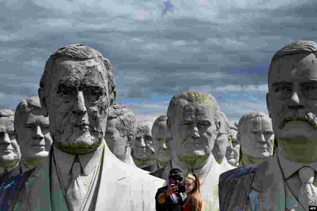 A couple takes a selfie with giant salvaged busts of former U.S. Presidents in Williamsburg, Virginia, Aug. 25, 2019. Howard Hankins rescued the giant busts of former U.S. Presidents from the closed Presidents Park in Colonial Williamsburg when he was commissioned to destroy them.