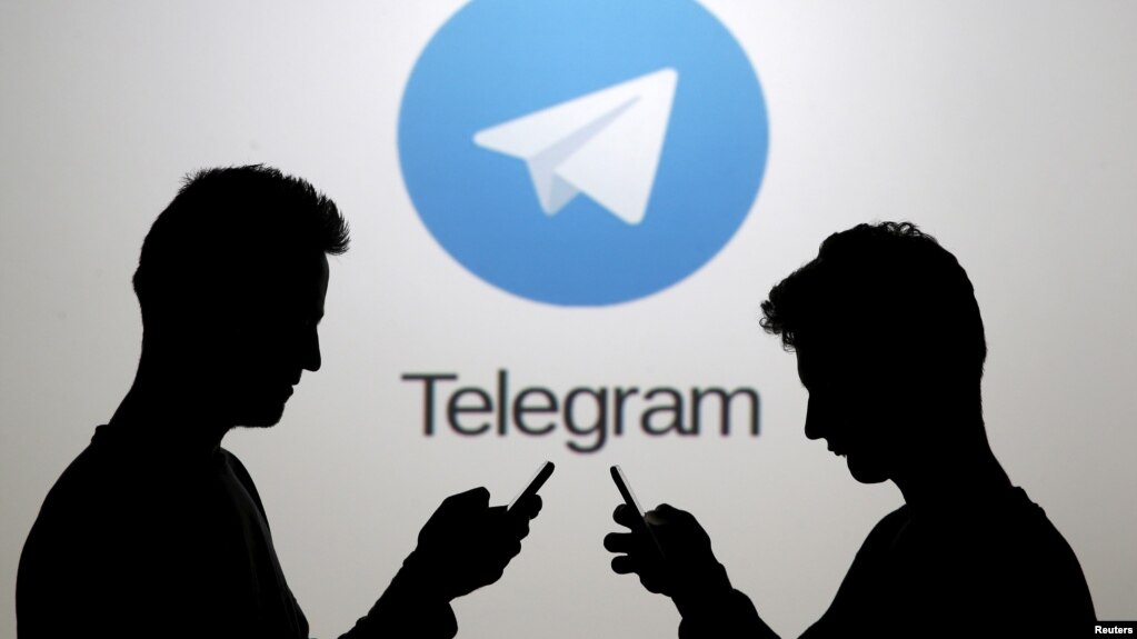 Two men pose with smartphones in front of a screen showing the Telegram logo in this picture illustration taken in Zenica, Bosnia and Herzegovina November 18, 2015. (REUTERS/Dado Ruvic)