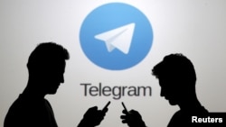 Deux hommes posent avec des smartphones devant le logo de Telegram, Zenica, en Bosnie-Herzégovine le 18 novembre 2015.