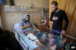 Mahmoud Barakat, lies in bed as a friend visits him at the Shifa hospital in Gaza, April 9, 2018. Barakat is among the nearly 1,300 people that Palestinian health officials said have been shot and wounded by Israeli soldiers during mass border protests.