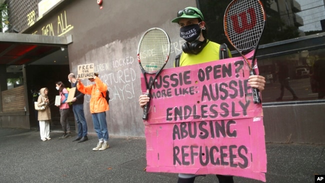 Protesters hold banners outside the Park Hotel calling for the release of refugees being detained inside in Melbourne, Australia, Jan. 8, 2022.
