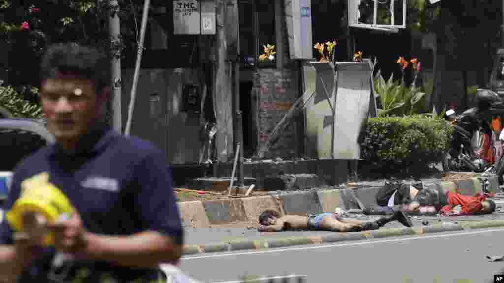 Bodies lie in front of a damaged police post as an Indonesia police official walks nearby after an explosion in Jakarta, Indonesia, Thursday, Jan. 14, 2016. 