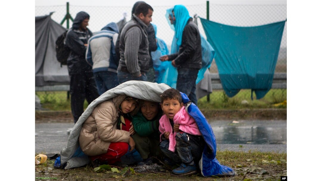 Children take shelter from the rain in Sredisce ob Dravi, a border crossing between Croatia and Slovenia, Oct. 19, 2015.