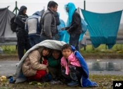 Children take shelter from the rain in Sredisce ob Dravi, a border crossing between Croatia and Slovenia, Oct. 19, 2015.
