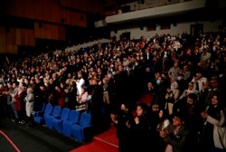 The audience stands for Iraqi virtuoso oud player Naseer Shamma as he performs, at the Iraqi National Theater in Baghdad, Iraq, Friday, Jan. 21, 2022. (AP Photo/Hadi Mizban)