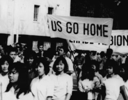 Teenage schoolgirls carry banners like "US Go Home" and "Perfidious Albion" through the street on March 11, 1964, in Phnom Penh before they sacked the US Embassy there. (AP Photo)