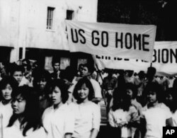 Teenage schoolgirls carry banners like "US Go Home" and "Perfidious Albion" through the street on March 11, 1964, in Phnom Penh before they sacked the US Embassy there. (AP Photo)