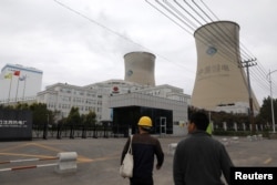 FILE - People walk past a China Energy coal-fired power plant in Shenyang, Liaoning province, China, Sept. 29, 2021.