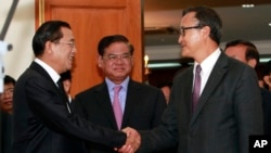 Cambodian Prime Minister Hun Sen, left, shakes hands with opposition party leader Sam Rainsy, right, after a meeting, as Sar Kheng, center, deputy prime minister, looks on at the National Assembly in Phnom Penh, file photo. 