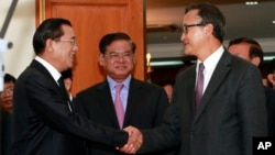 Cambodian Prime Minister Hun Sen, left, shakes hands with opposition party leader Sam Rainsy, right, after a meeting, as Sar Kheng, center, deputy prime minister, looks on at the National Assembly in Phnom Penh, Cambodia, Monday, Sept. 16, 2013. Hun Sen and Sam Rainsy met for the second time on Monday in a bid to resolve a political stalemate, a day after violent clashes on the streets of Phnom Penh. (AP Photo/Heng Sinith)