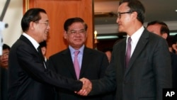 Cambodian Prime Minister Hun Sen, left, shakes hands with opposition party leader Sam Rainsy, right, after a meeting, as Sar Kheng, center, deputy prime minister, looks on at the National Assembly in Phnom Penh, file photo. 