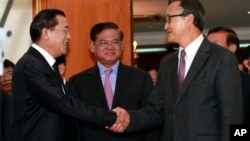 Cambodian Prime Minister Hun Sen, left, shakes hands with opposition party leader Sam Rainsy, right, after a meeting, as Sar Kheng, center, deputy prime minister, looks on at the National Assembly in Phnom Penh, Cambodia, Monday, Sept. 16, 2013.