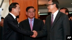 Cambodian Prime Minister Hun Sen, left, shakes hands with opposition party leader Sam Rainsy, right, after a meeting, as Sar Kheng, center, deputy prime minister, looks on at the National Assembly in Phnom Penh, file photo. 