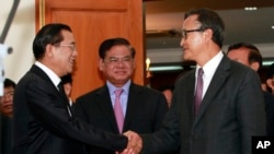 Cambodian Prime Minister Hun Sen, left, shakes hands with opposition party leader Sam Rainsy, right, after a meeting, as Sar Kheng, center, deputy prime minister, looks on at the National Assembly in Phnom Penh, file photo. 