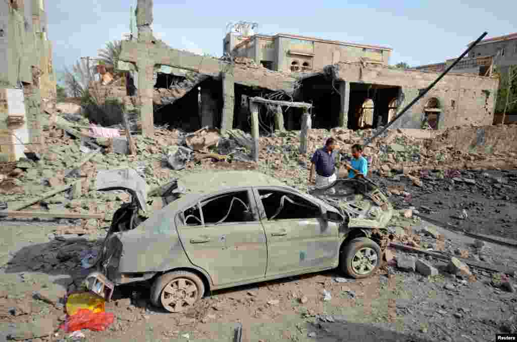 People stand at the site of a Saudi-led airstrike in the Red Sea port city of Houdieda, Yemen.