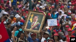 A government supporter holds up a framed image of President Nicolas Maduro during an anti-imperialist rally in Caracas, Venezuela, Saturday, March 30, 2019. 