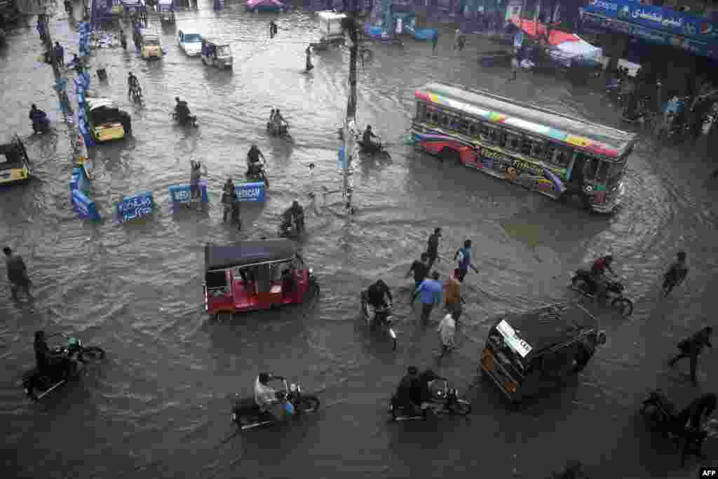 Commuters make their way along a flooded street after heavy monsoon rains in Pakistan&#39;s port city of Karachi, Pakistan.