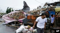 Seorang warga berjalan melewati kios-kios yang rusak di pasar umum ketika Topan Mangkhut berlar di kota Tuguegarao di provinsi Cagayan, Filipina timur laut, 15 September 2018. 