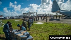 Sailors assigned to the U.S. Navy's forward-deployed aircraft carrier USS George Washington, Marines assigned to the 3 Marine Expeditionary Brigade, and Philippine civilians unload relief supplies in support of Operation Damayan. ((U.S. Navy photo by Mass Communication Specialist Seaman Beverly Lesonik)