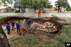 Men repair a road damaged by Cyclone Kenneth in Pemba city on the northeastern coast of Mozambique, April, 27, 2019.