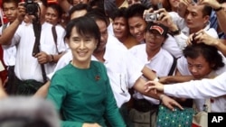 Burma's pro-democracy leader Aung San Suu Kyi greets supporters as she leaves her National League for Democracy party following her meeting with newly elected lawmakers at the party headquarters in Rangoon, April. 7, 2012.